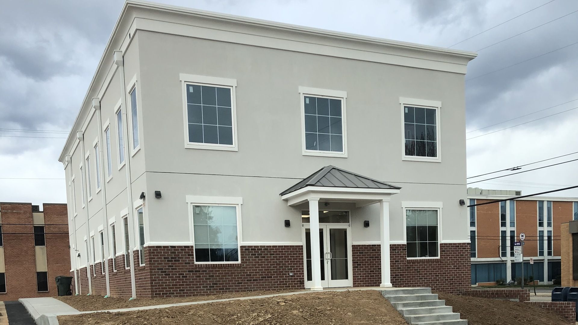 A large white building with stairs leading up to it is sitting on top of a hill.