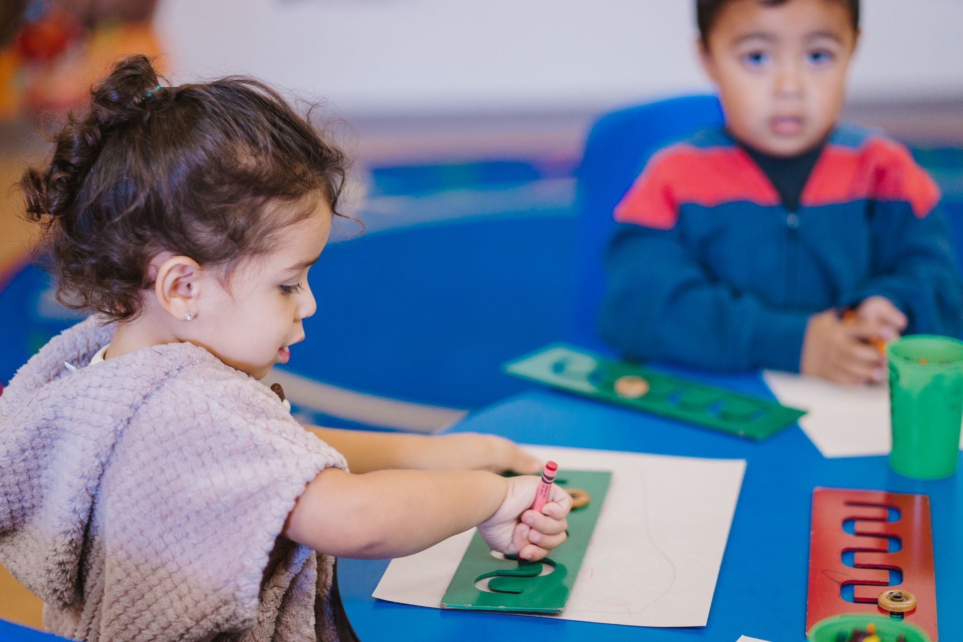 A boy and a girl are sitting at a table playing with toys