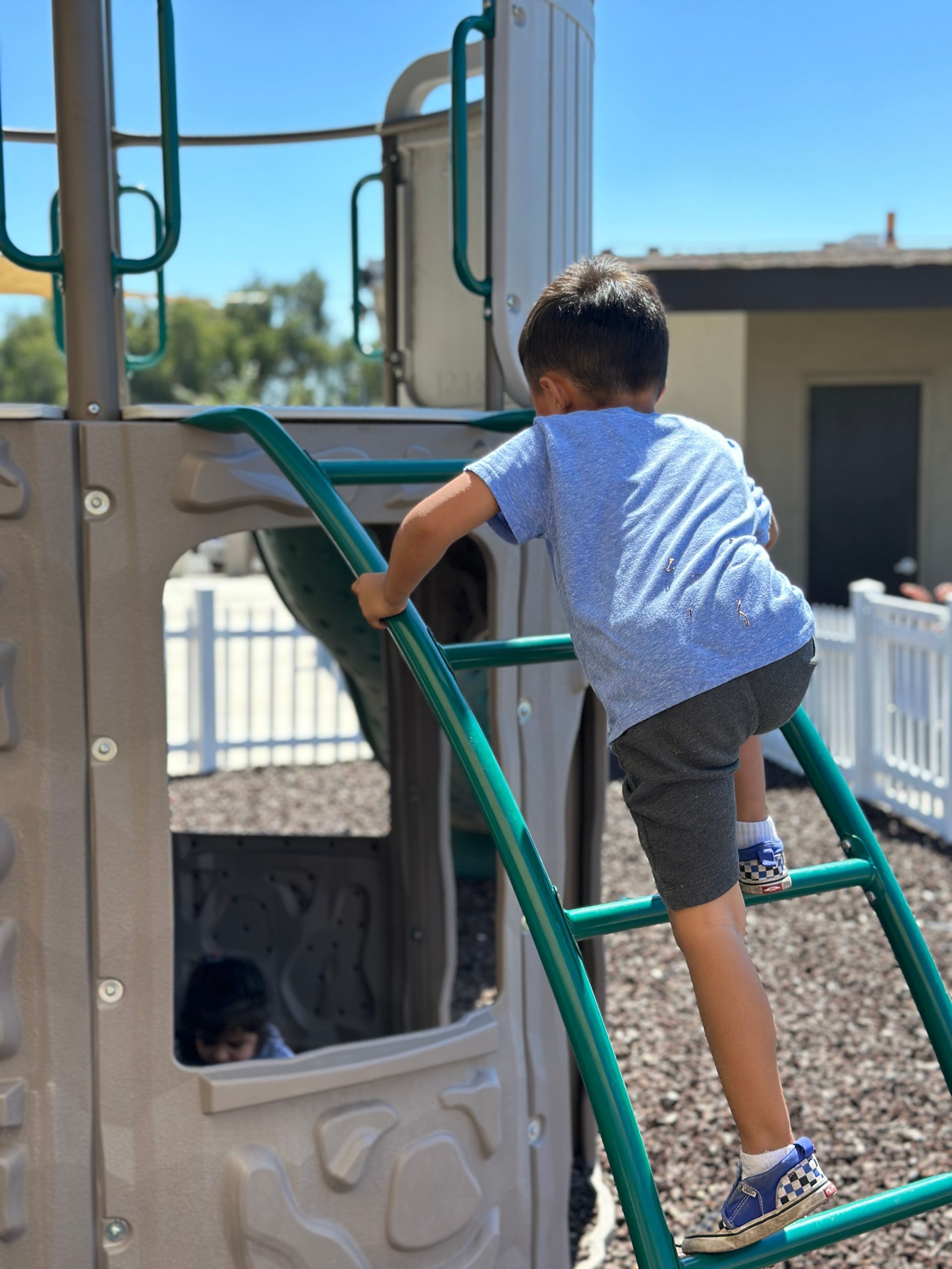 A young boy is climbing up a ladder at a playground