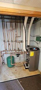 A room with a boiler and pipes in it.