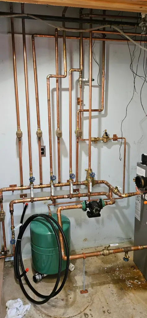 A room filled with copper pipes and a green tank.