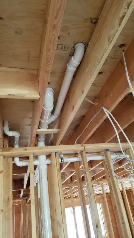A house under construction with a lot of pipes coming out of the ceiling.