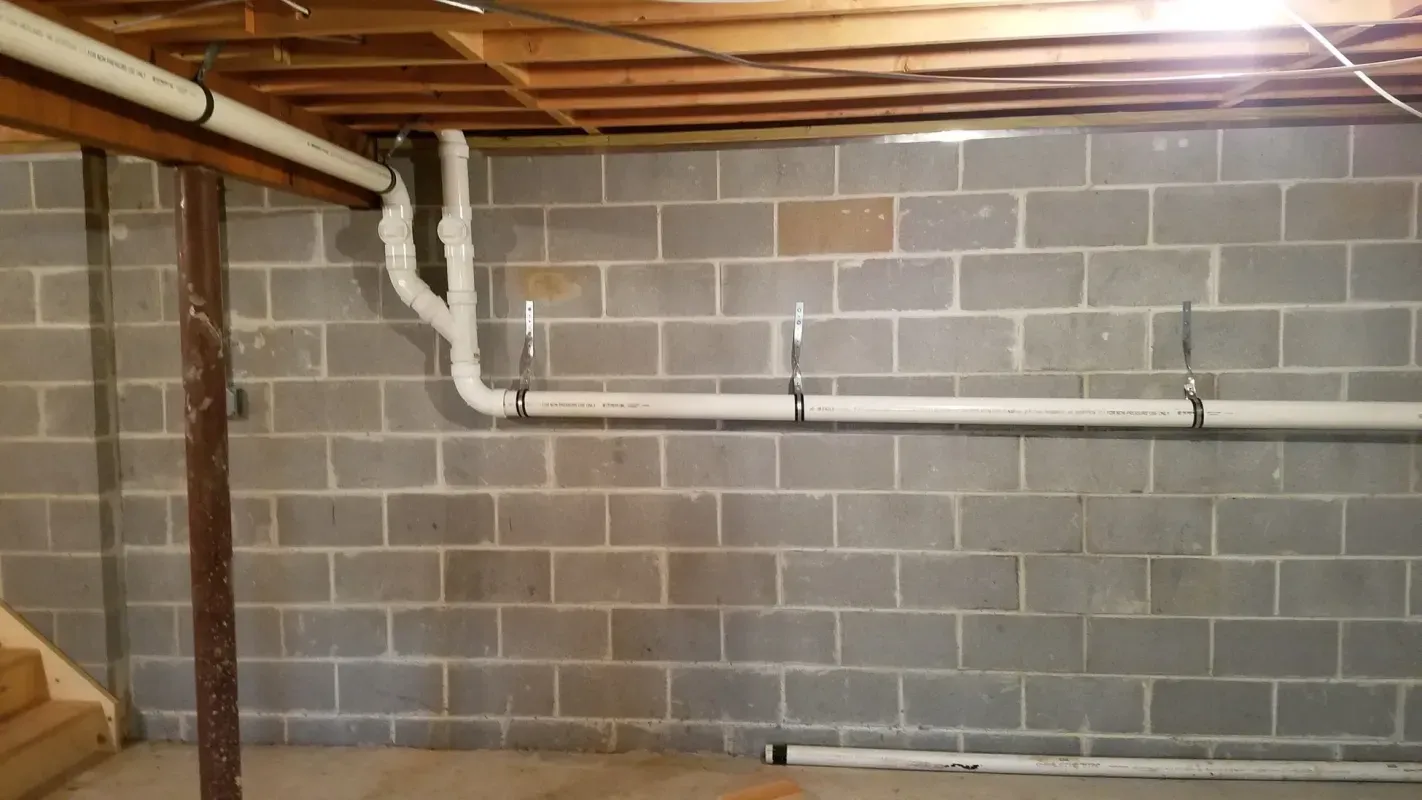 A basement with a brick wall and pipes coming out of it.