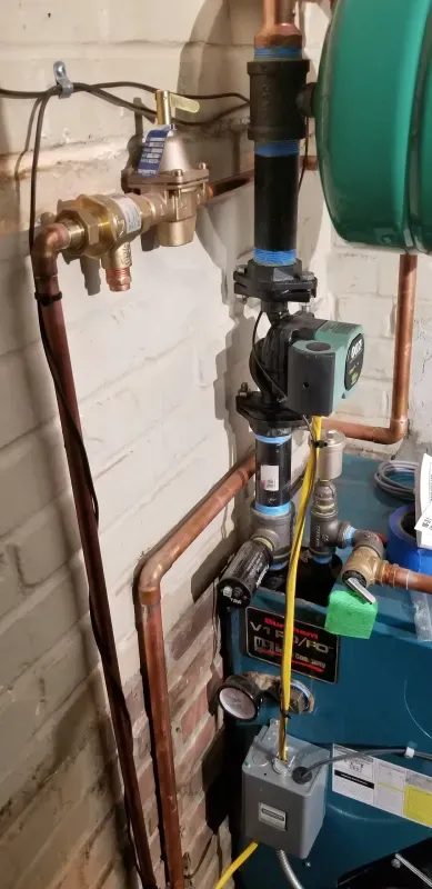 A close up of a boiler with a lot of pipes connected to it.