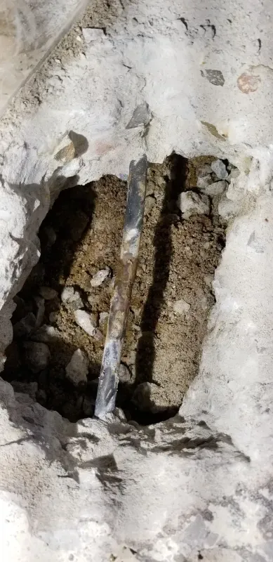 A hole in a wall with a piece of metal sticking out of it.