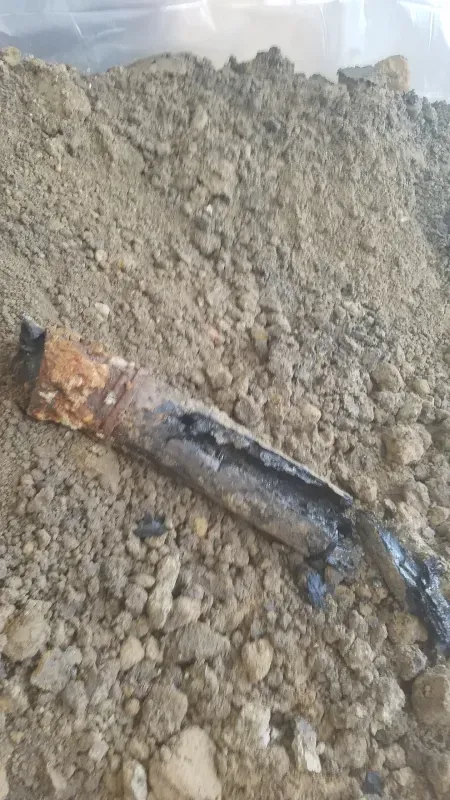 A piece of metal is laying on top of a pile of dirt.