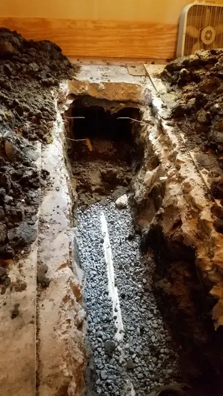 A hole in the ground in a room with a fan in the background.