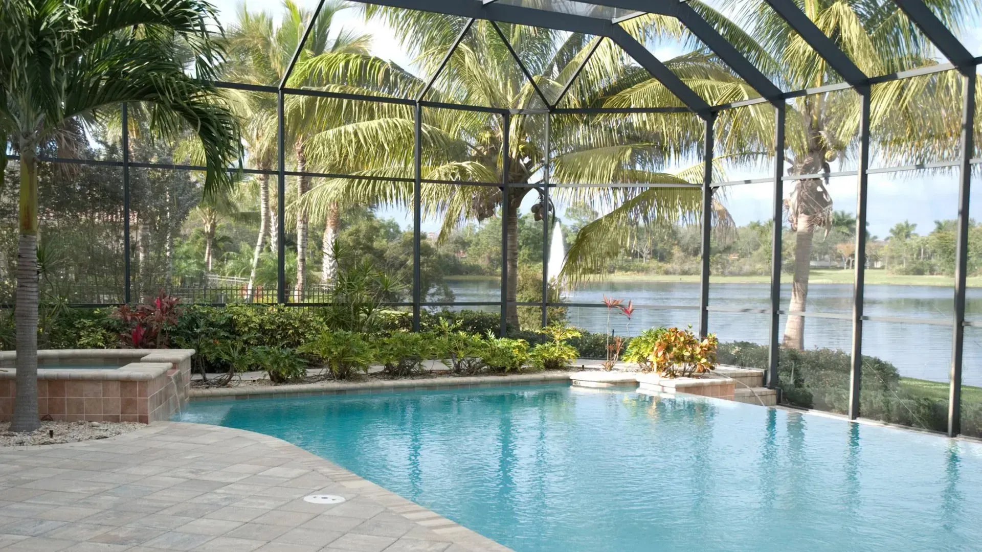 A screened in swimming pool with a view of a lake.