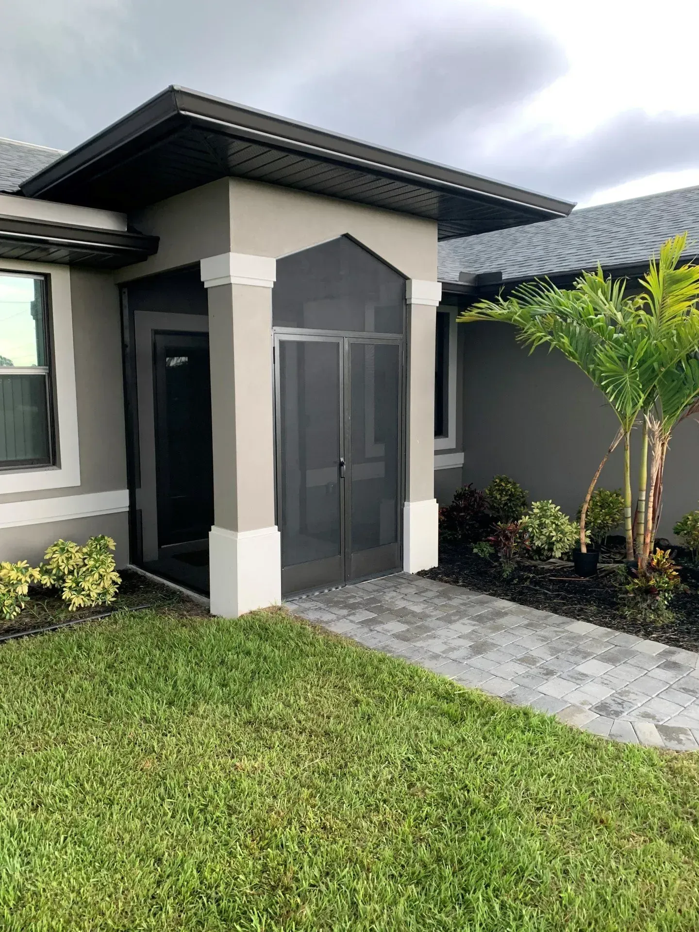A house with a screened in porch and a walkway leading to it.
