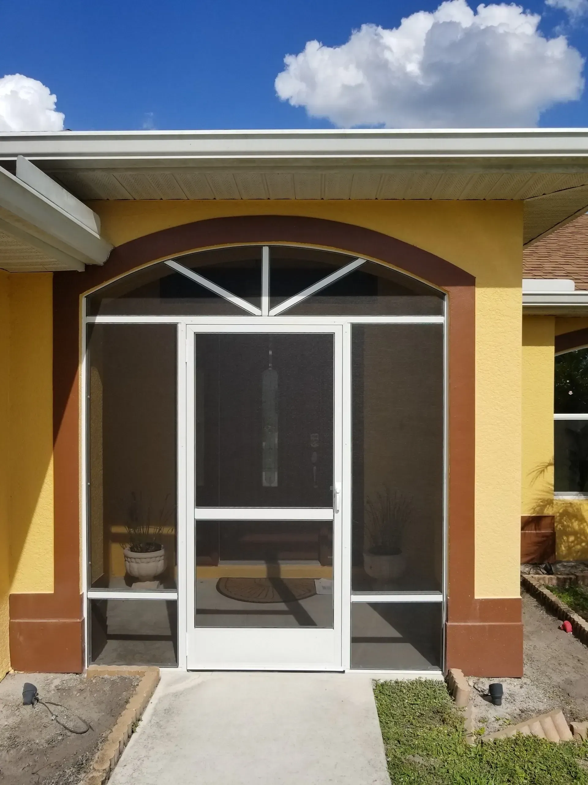 A yellow house with a screened in porch.