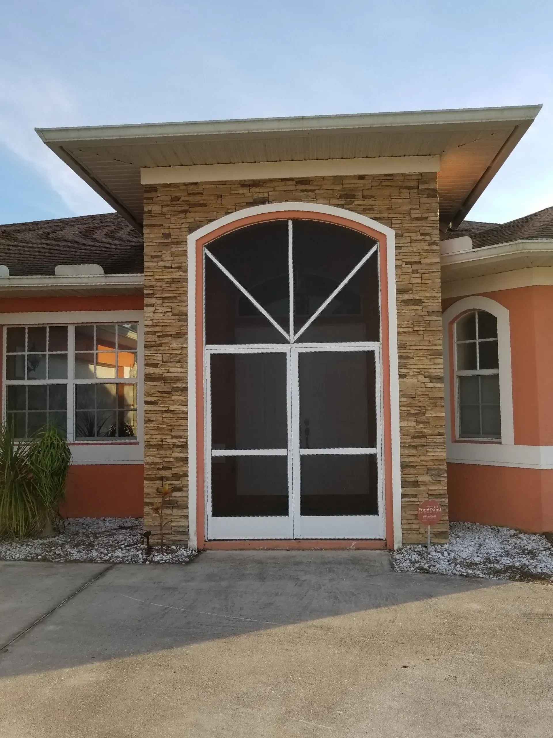 A house with a screen door and a stone facade.