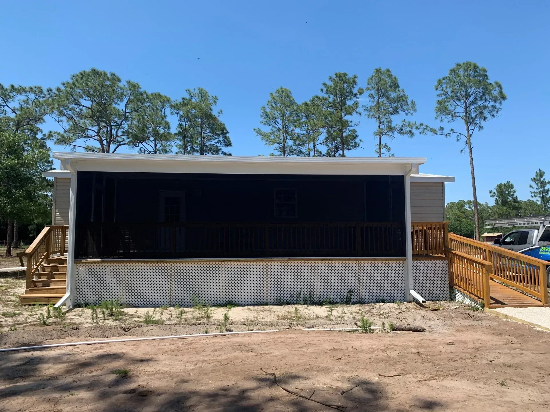 A mobile home with a screened in porch and a wooden deck.