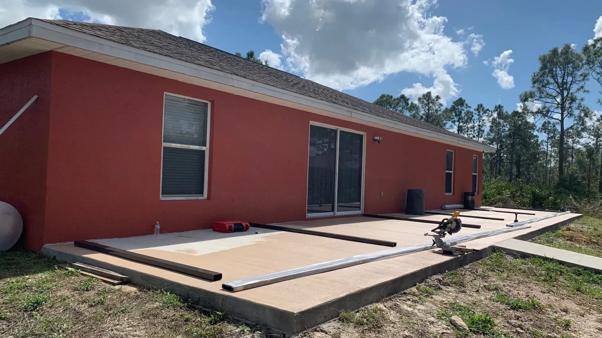 A red house with a patio in front of it is being built.