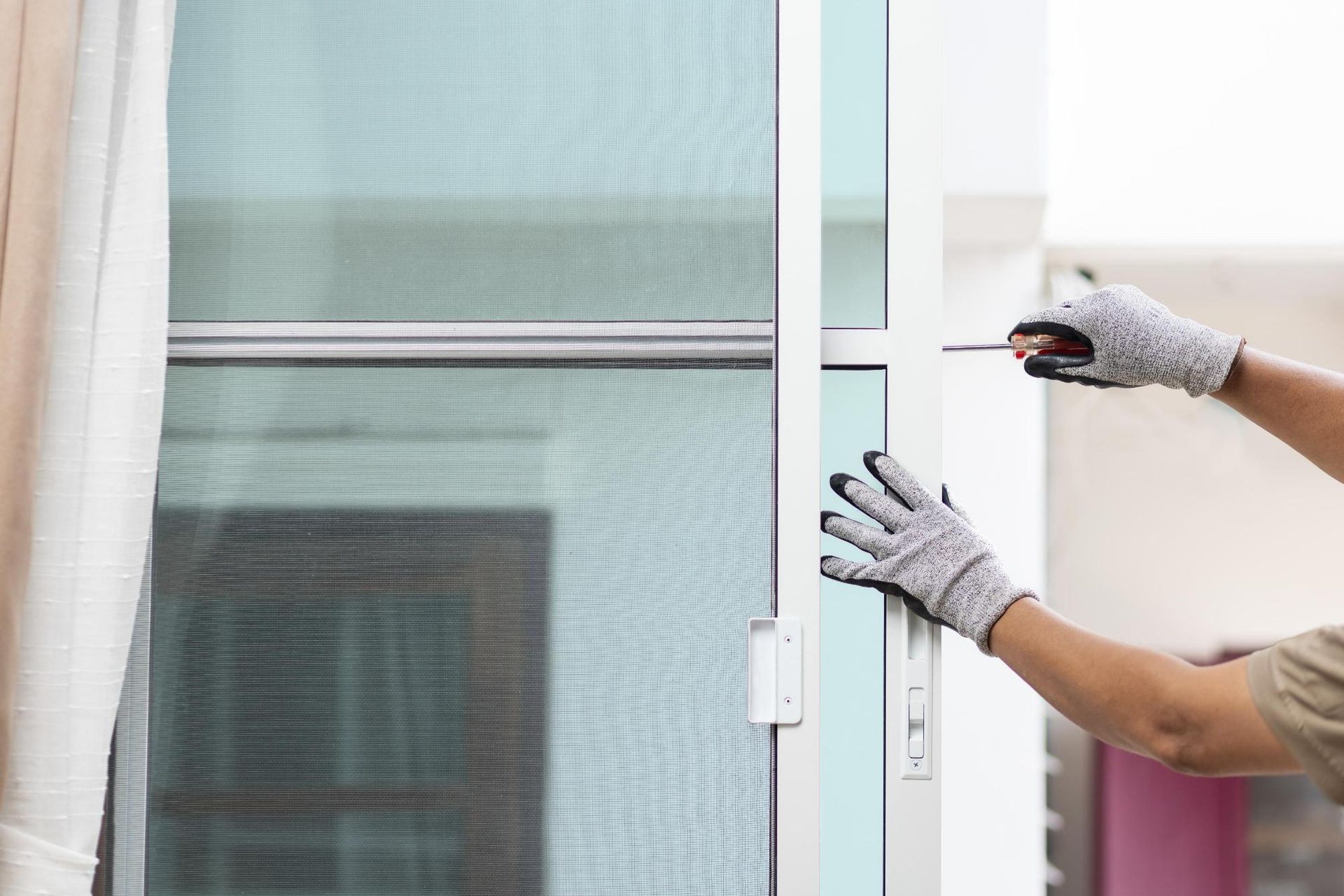 A person is installing a mosquito net on a sliding glass door.