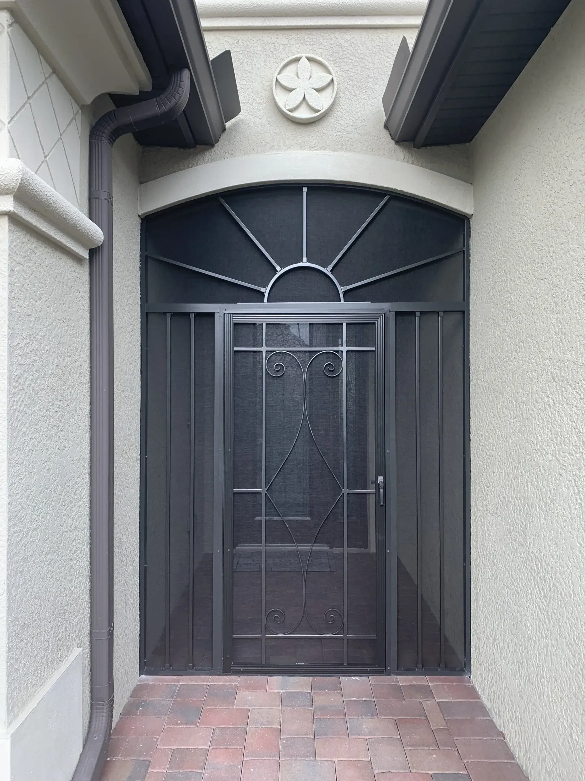 A black screen door with a stained glass window.