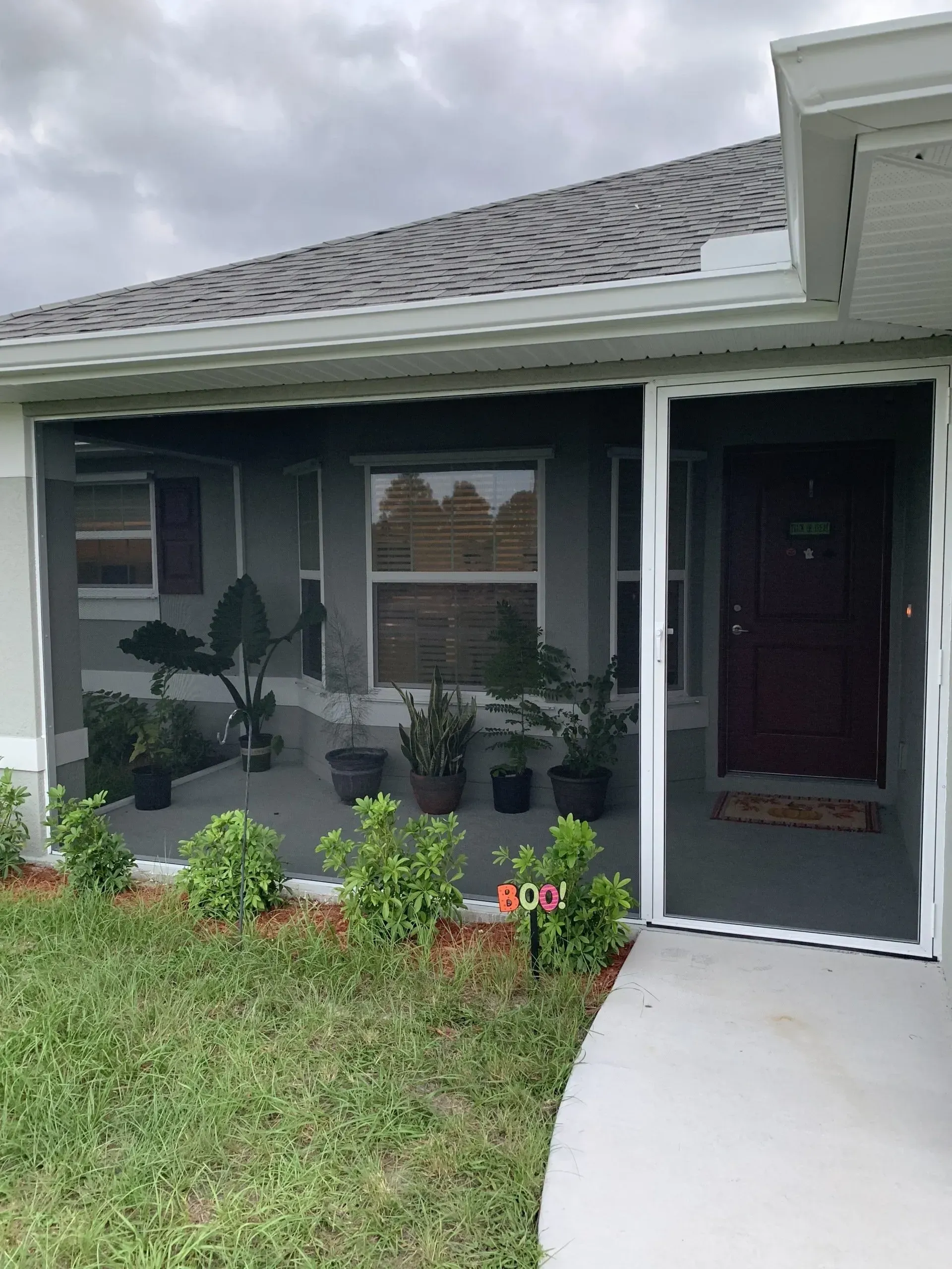 A house with a screened in porch and a red door.