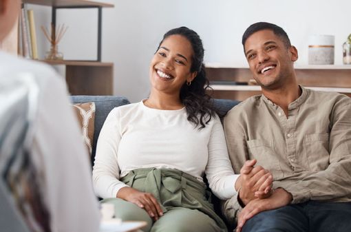 A man and a woman are sitting on a couch talking to a woman.