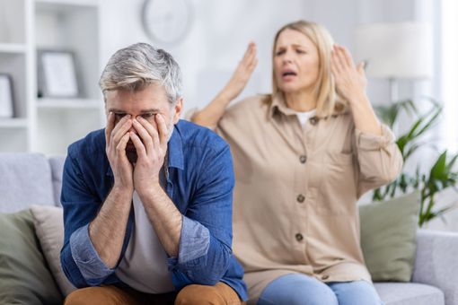 A man and a woman are sitting on a couch talking to a woman.
