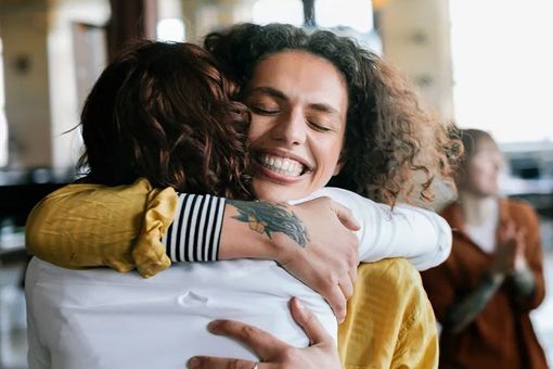 Two women are hugging each other and smiling.