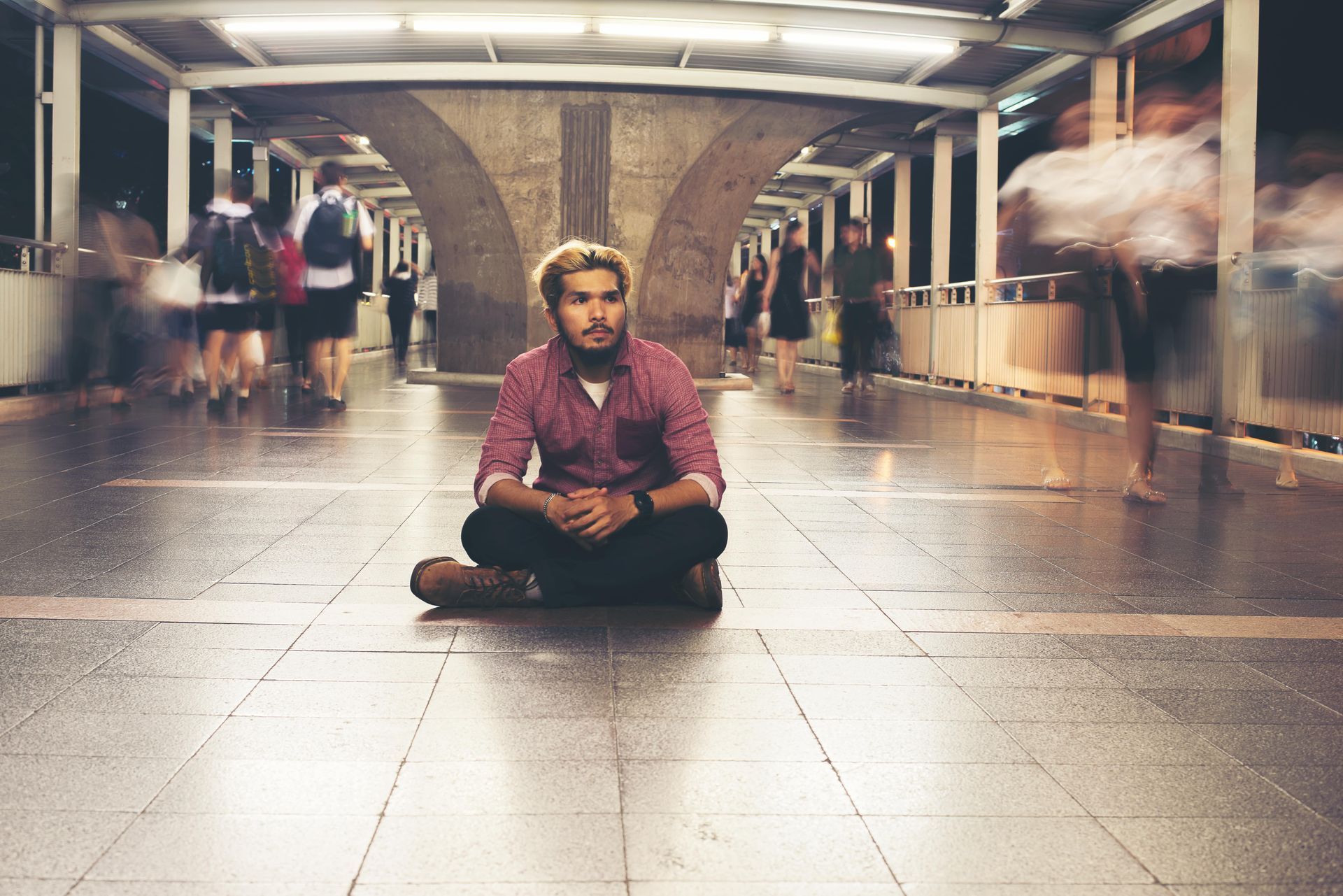 A man is sitting on the floor in front of a crowd of people.