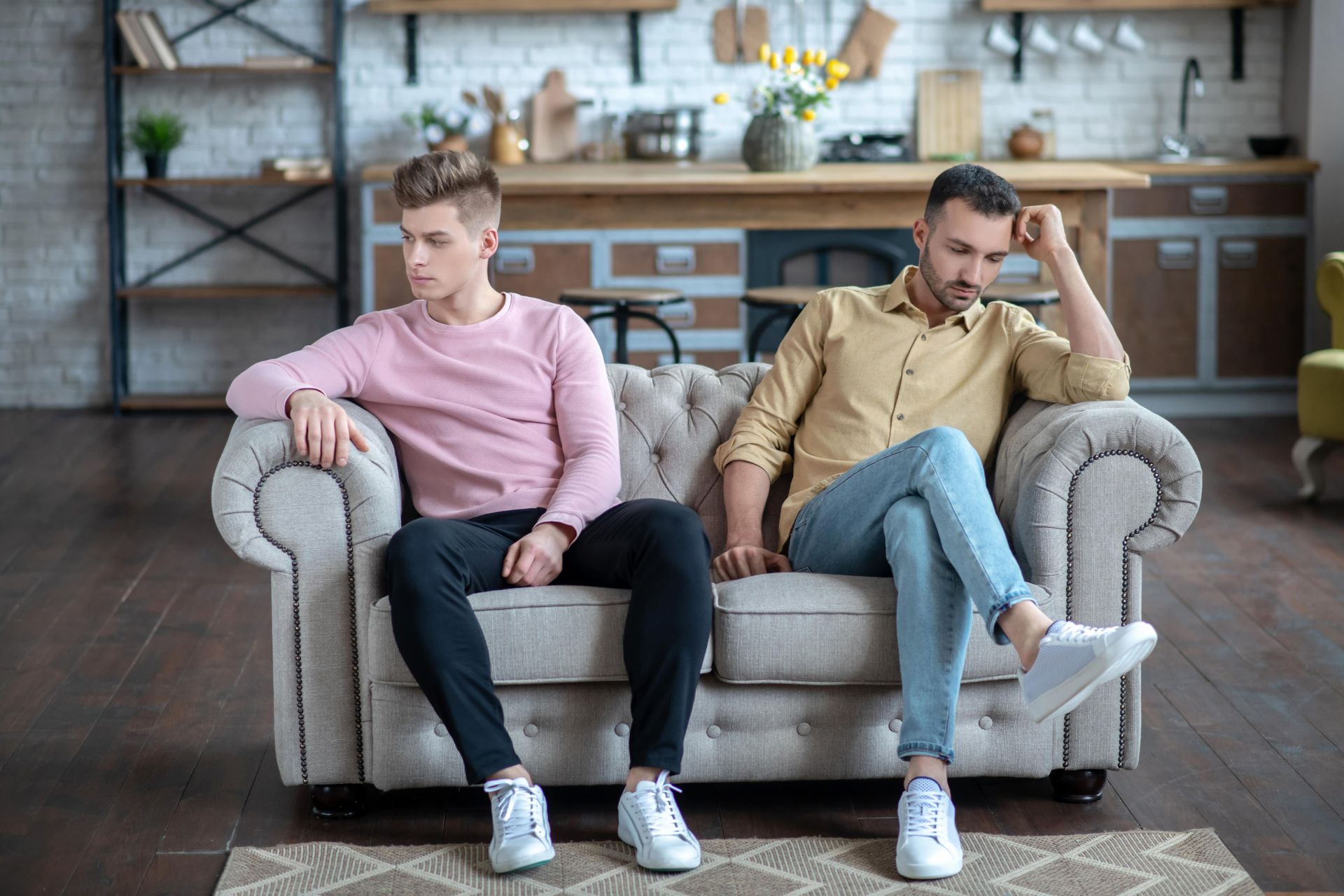 Two men are sitting on a couch looking at each other.