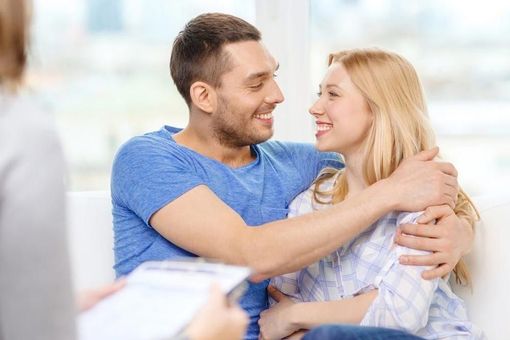 A man and a woman are sitting on a couch looking at each other.