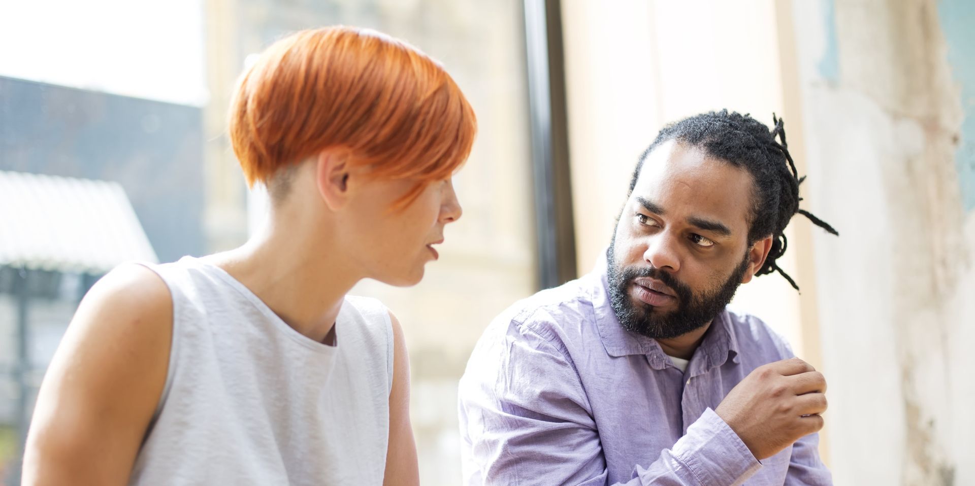A rainbow flag is waving in the wind against a blue sky.