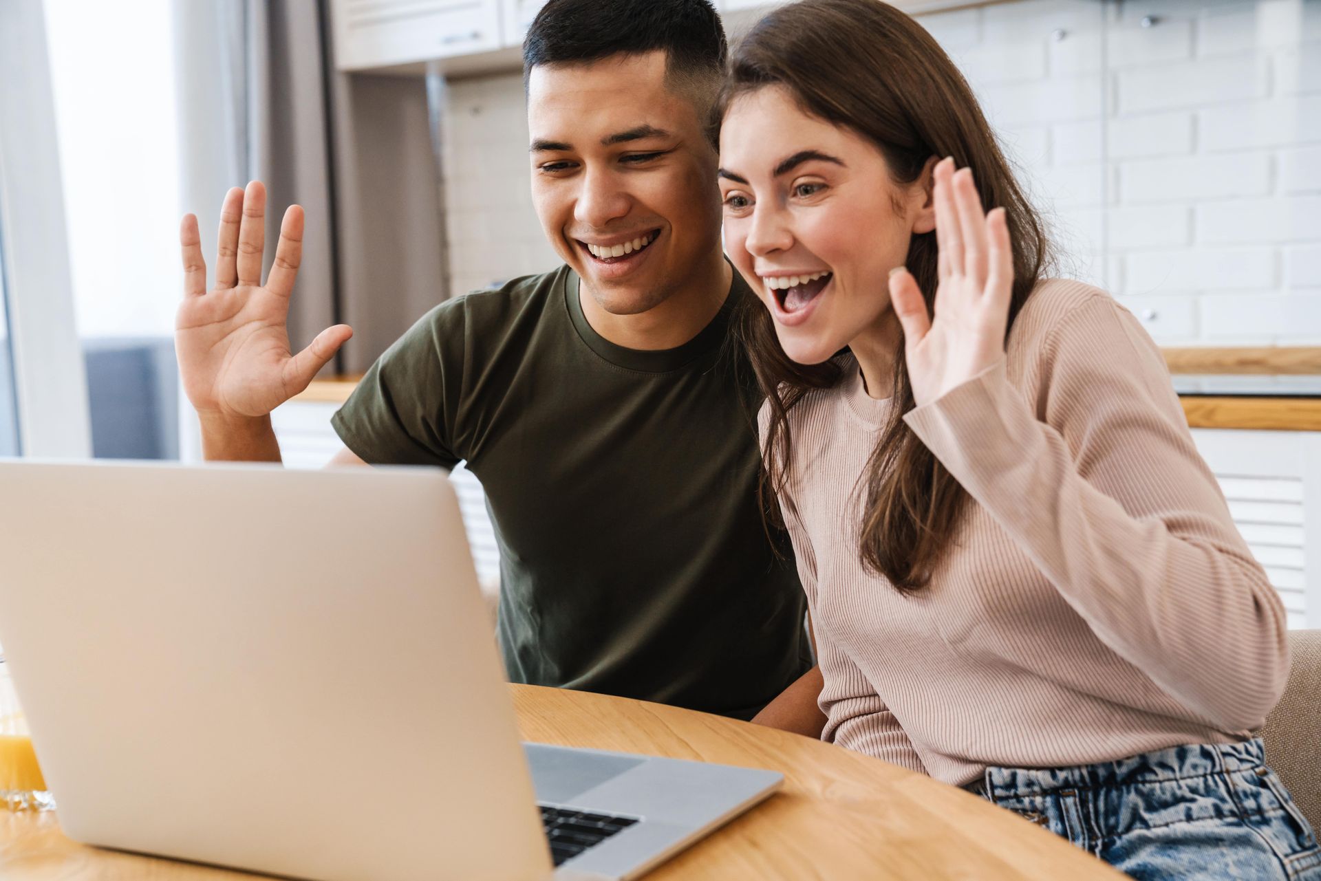 A man and a woman are sitting at a table using a laptop computer.