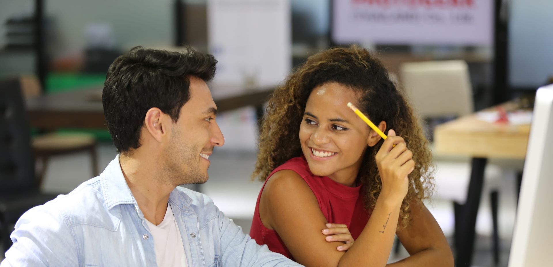 A rainbow flag is waving in the wind against a blue sky.