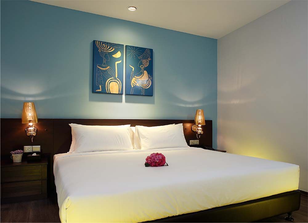 A hotel room with a king size bed and two paintings on the wall.