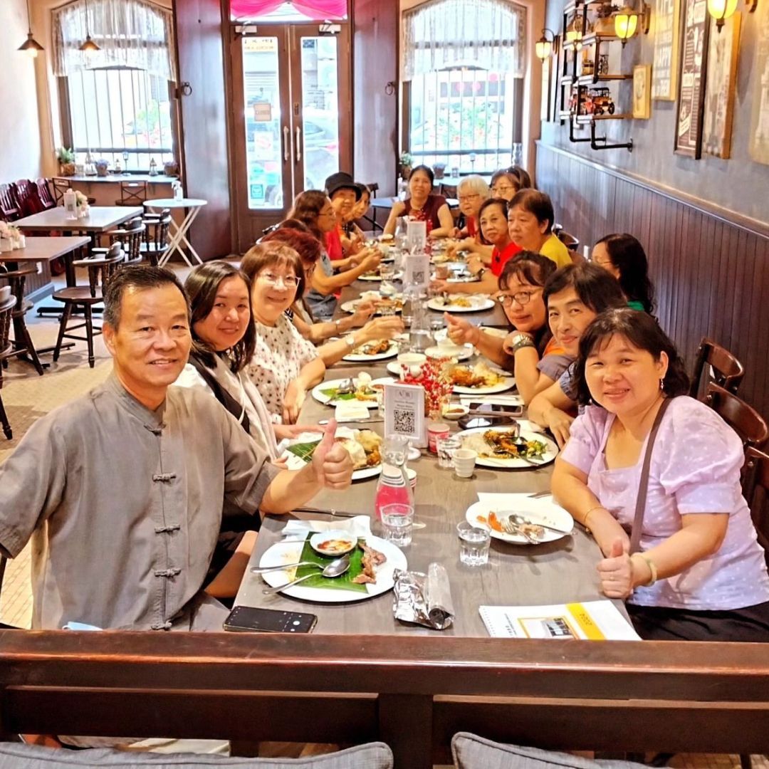 A group of people are sitting at a long table in a restaurant eating food.