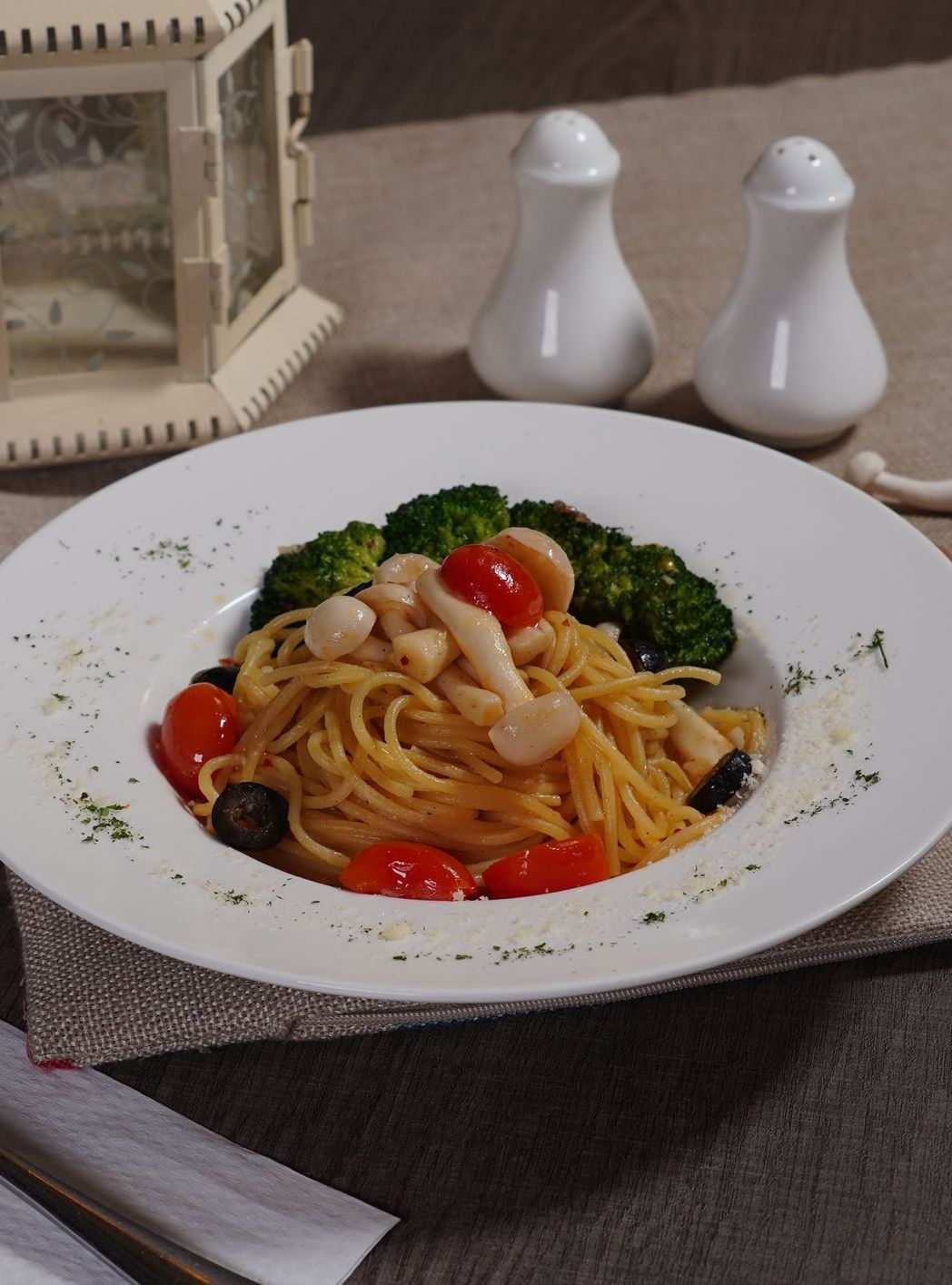 A plate of spaghetti with broccoli and tomatoes on a table