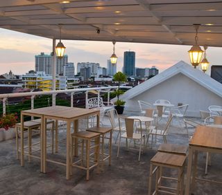 Tables and chairs on a rooftop with a city in the background