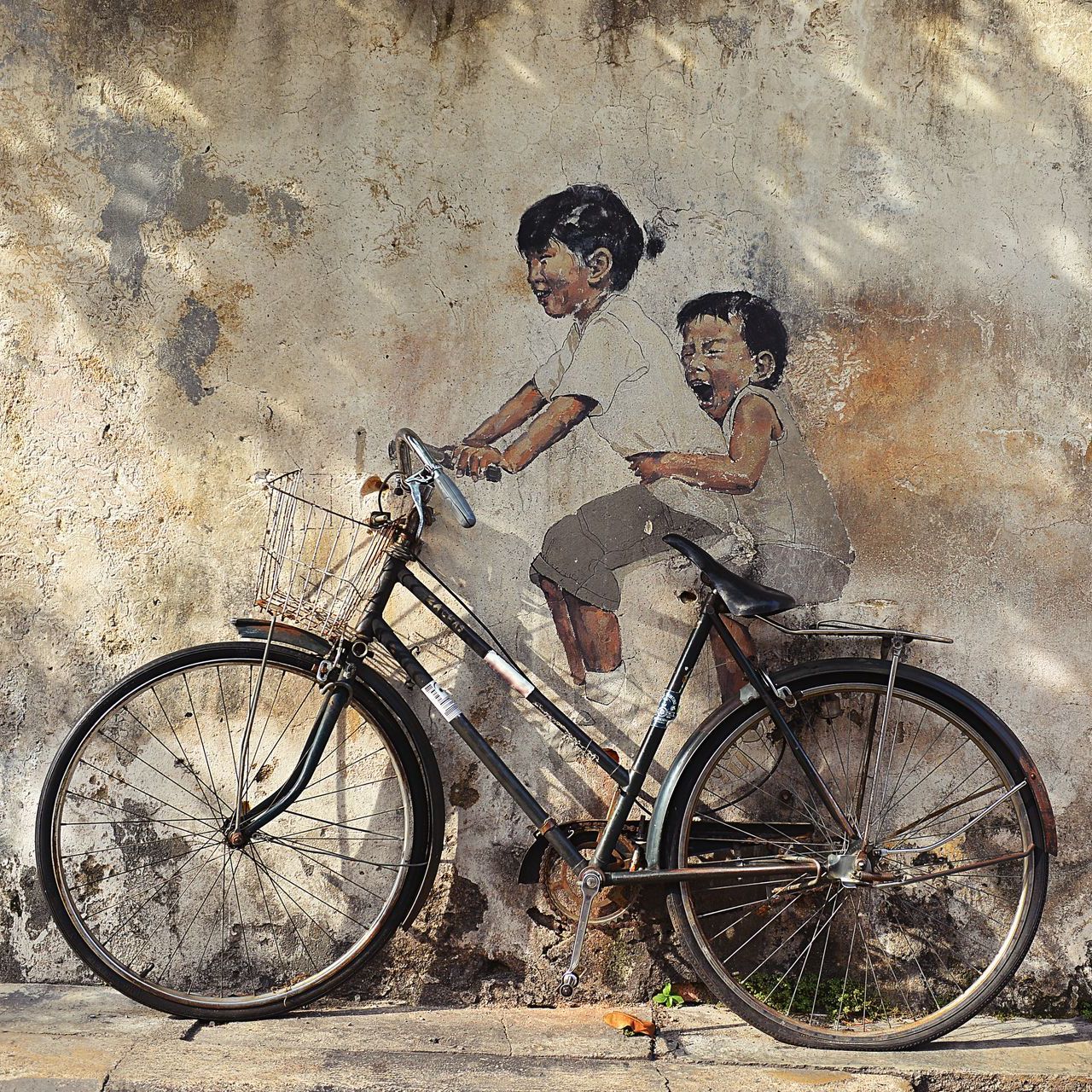 Image 40: A painting of two children riding a bike on a wall