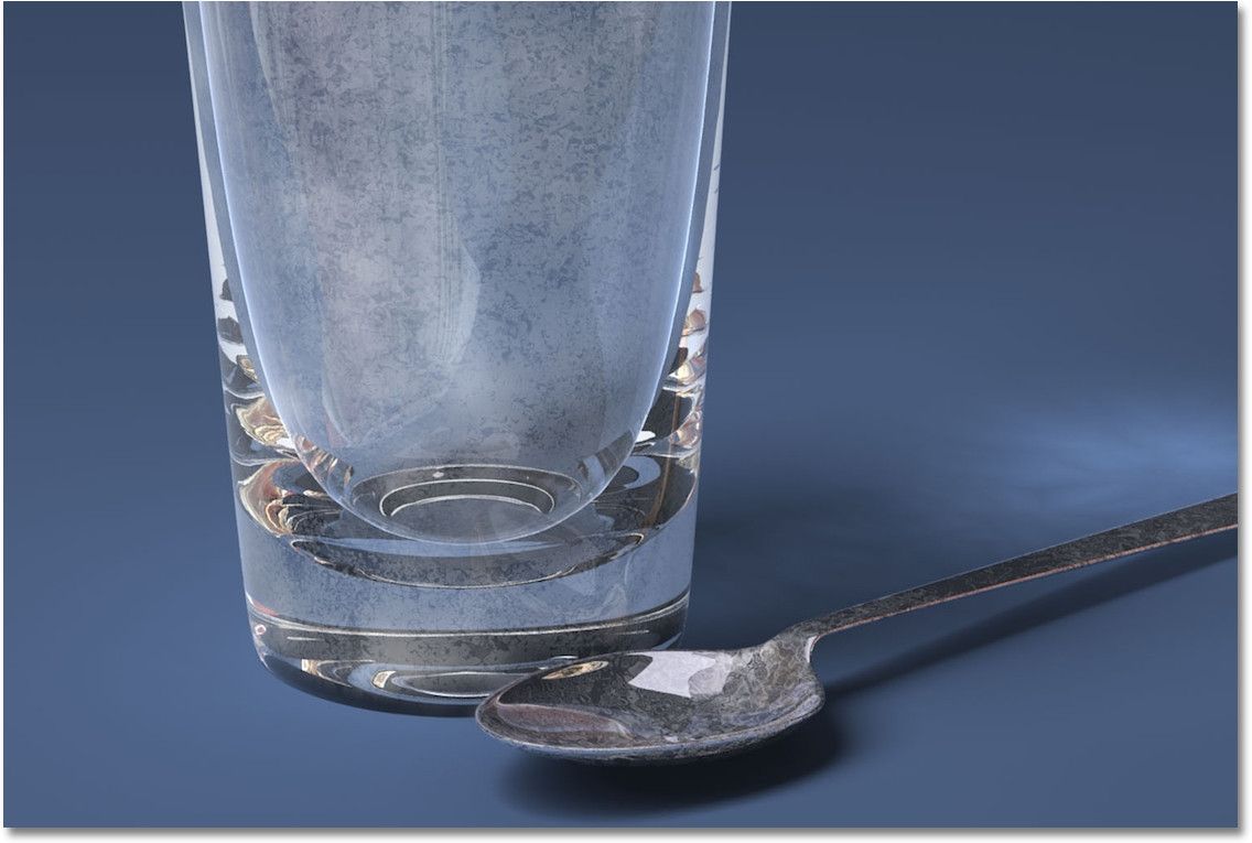 Close up photo of hard water film and scale left on a spoon and in a drinking glass.