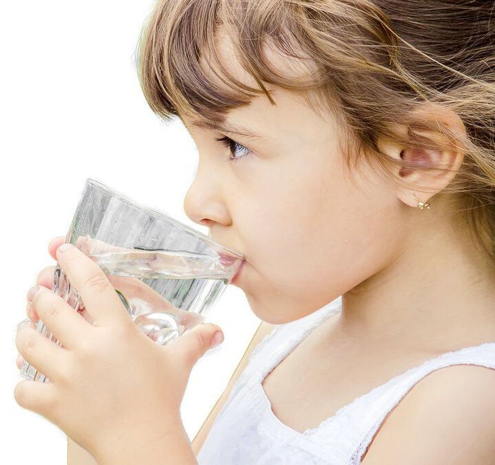 a little girl is drinking pure clean filtered water from a glass .