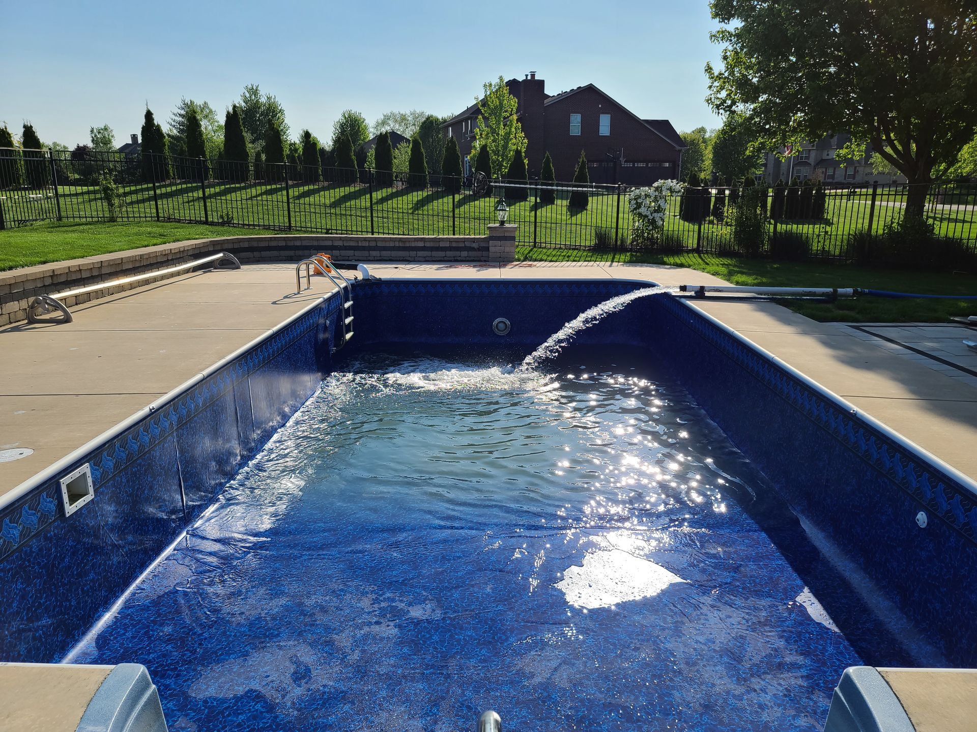 a large swimming pool with a house in the background