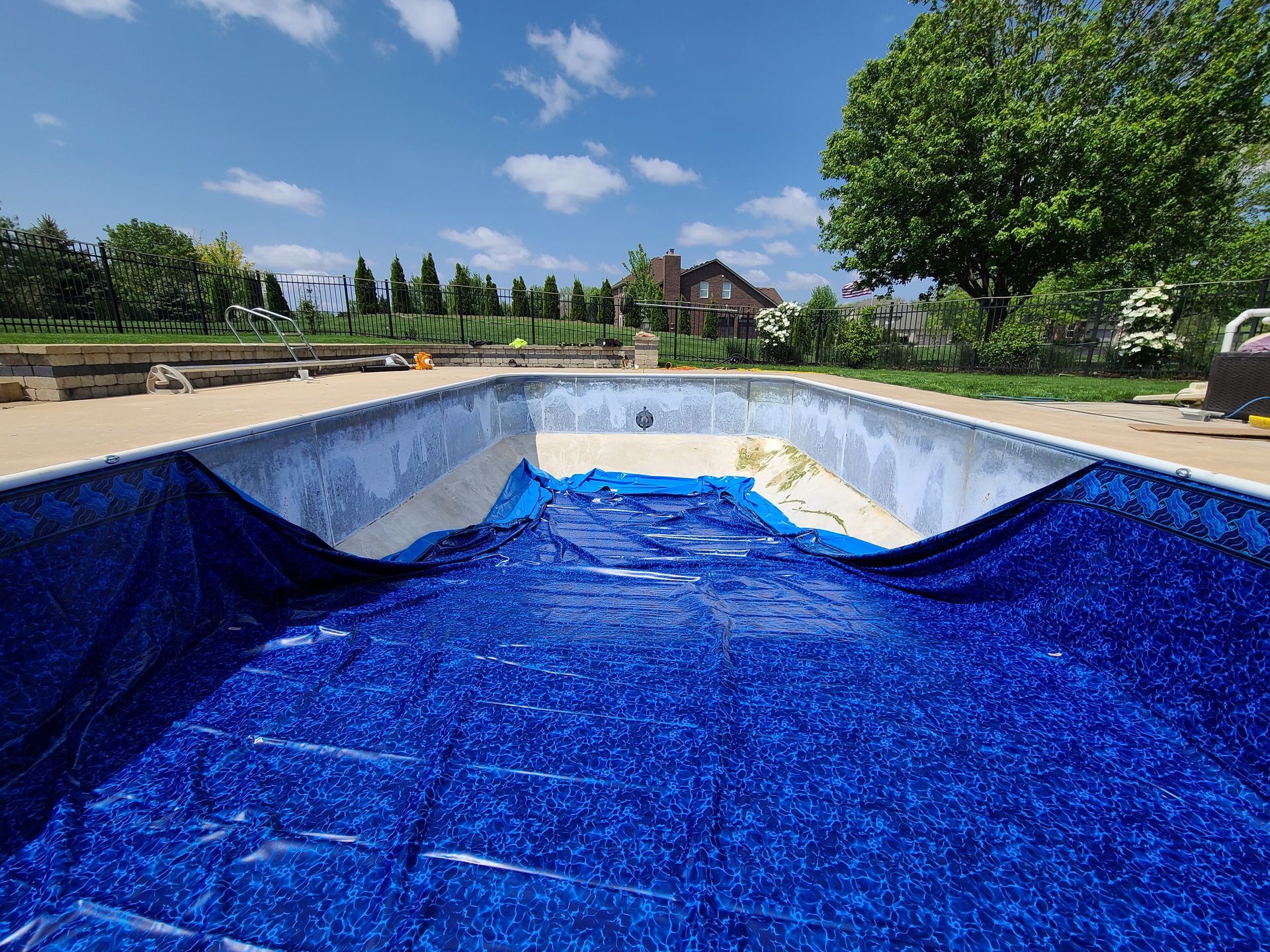 An empty swimming pool with a blue tarp on top of it.