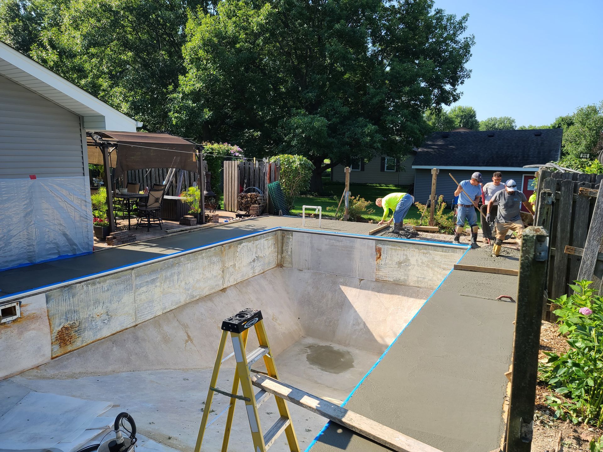 a group of people are working on a swimming pool in a backyard .