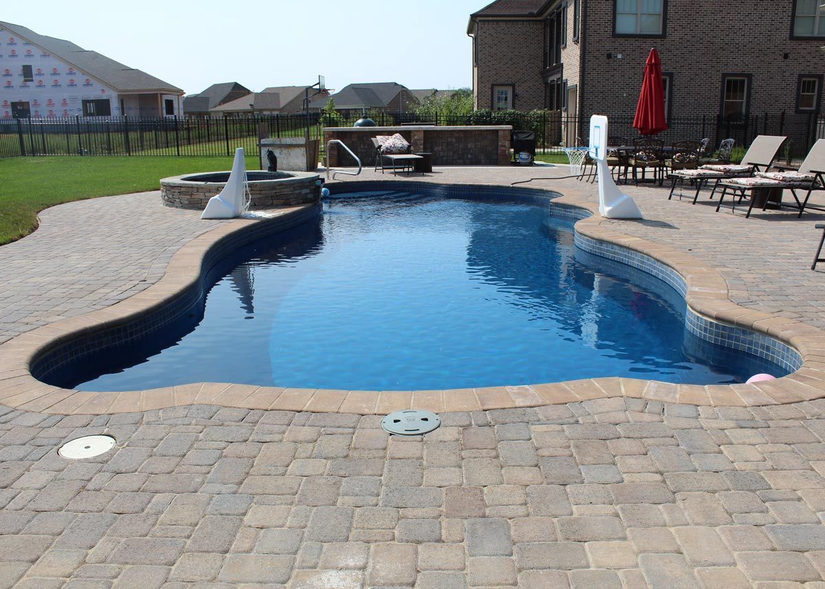 a large swimming pool is surrounded by a brick patio
