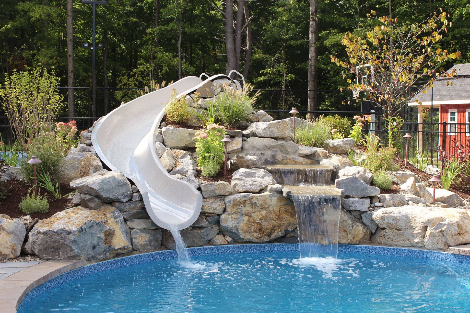 a pool with a water slide and a waterfall in the backyard