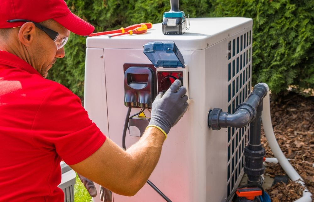 A man in a red shirt is working on a pool heater.