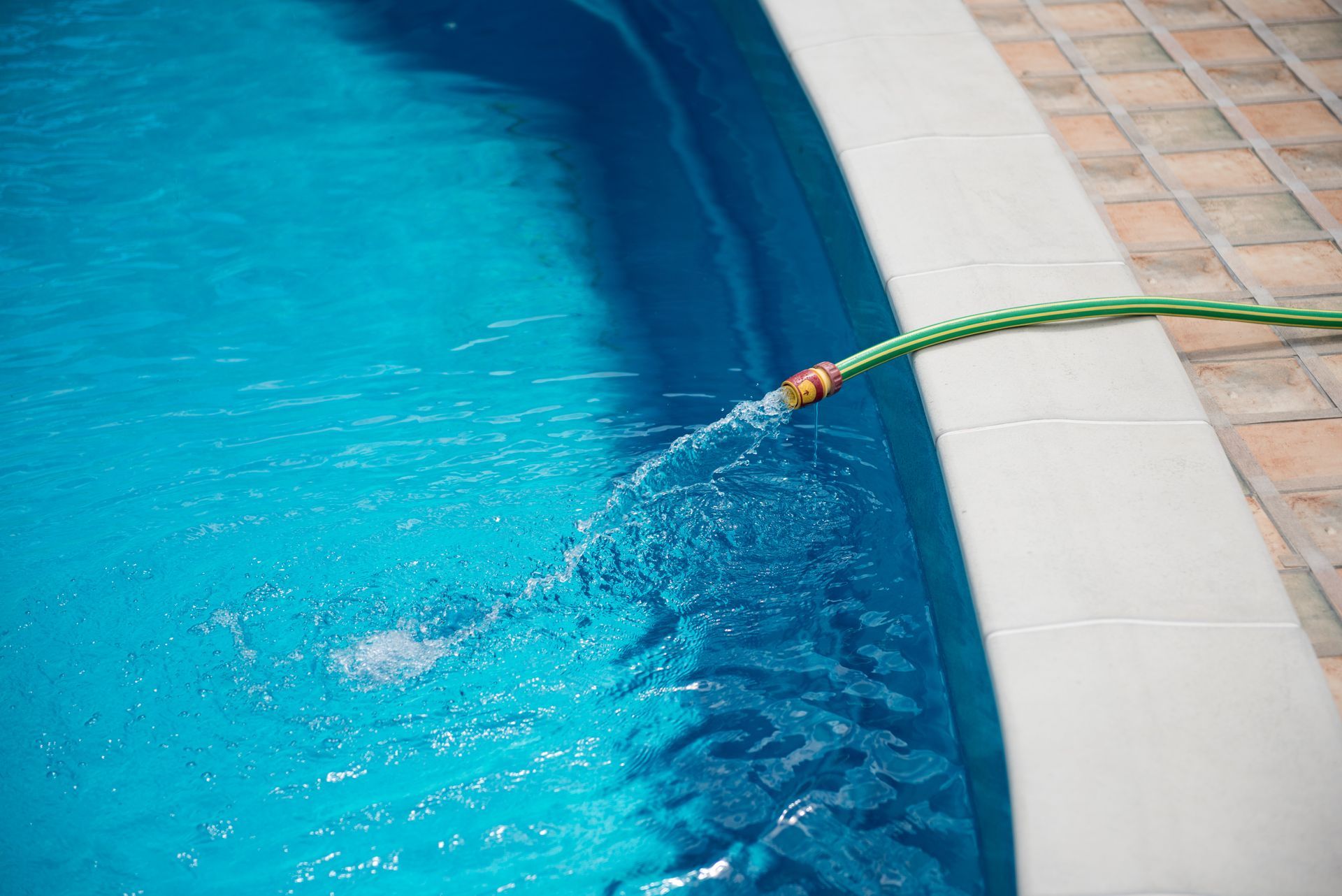 green hose adding water to the pool to open it for the summer