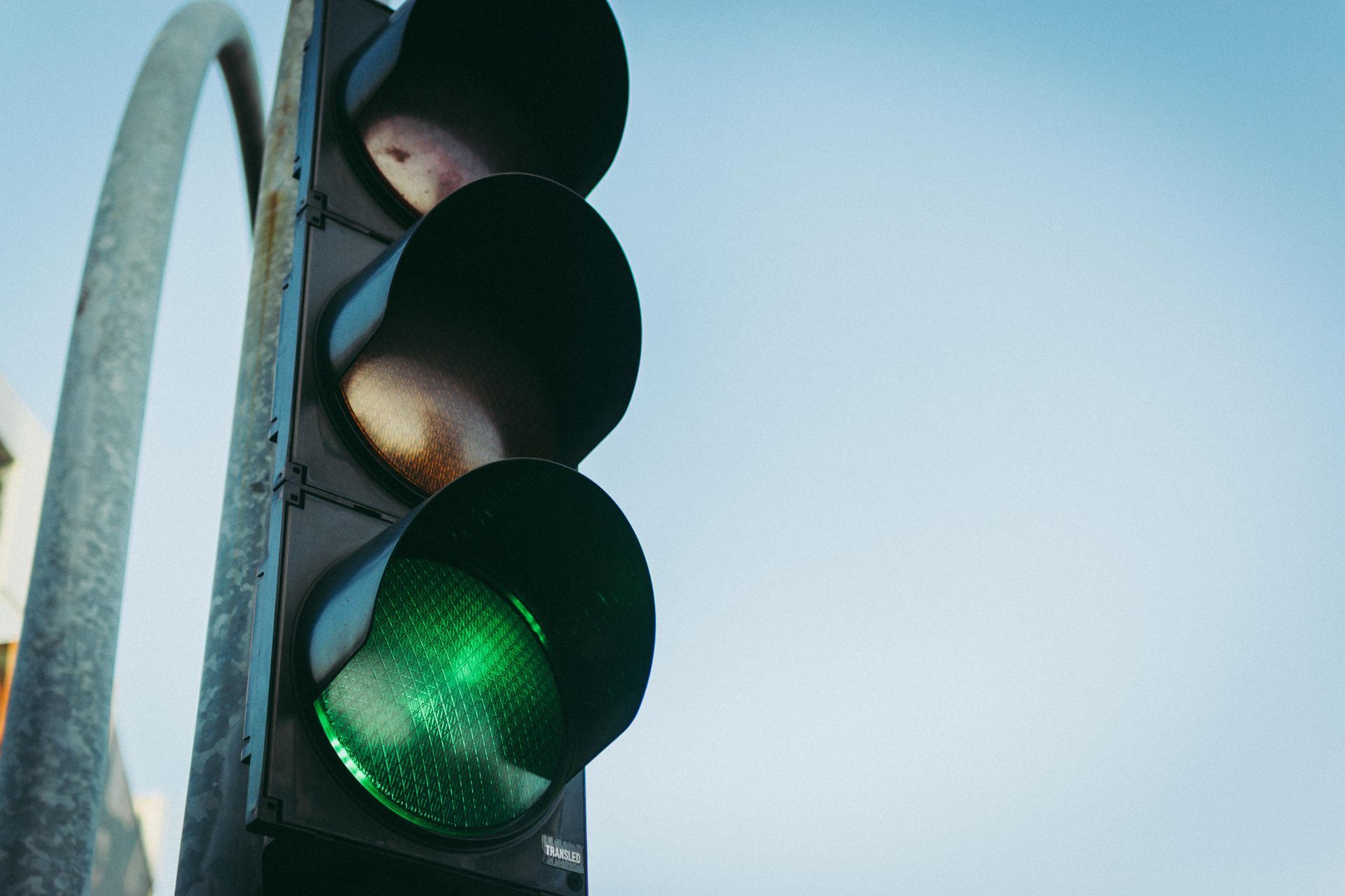 Green traffic light against a light blue sky.