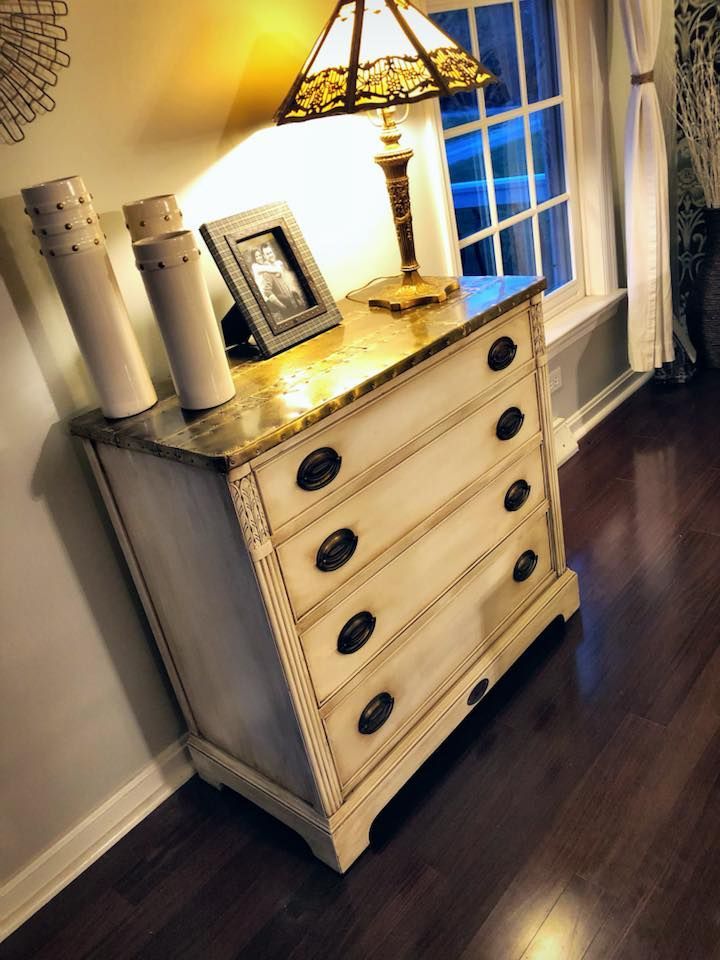 A dresser with a lamp and a picture on top of it