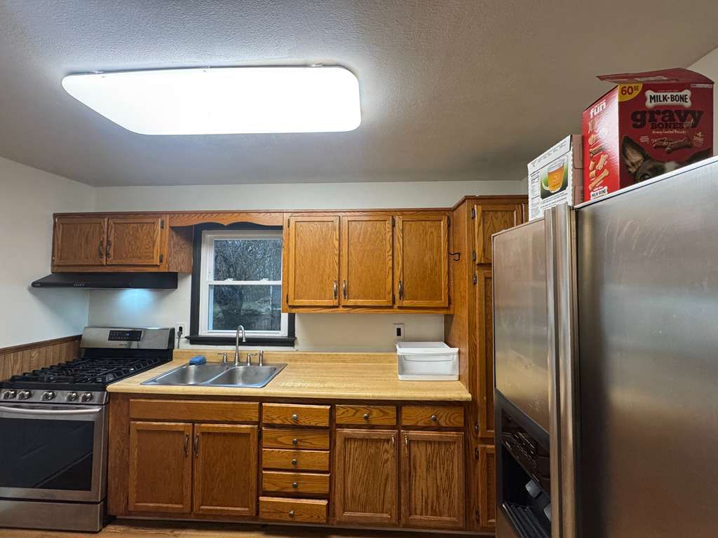 Kitchen with wooden cabinets, stainless steel appliances, and a window above the sink.