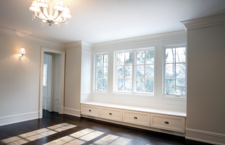 Bright room with dark floor, white trim, and a window seat with drawers under windows.