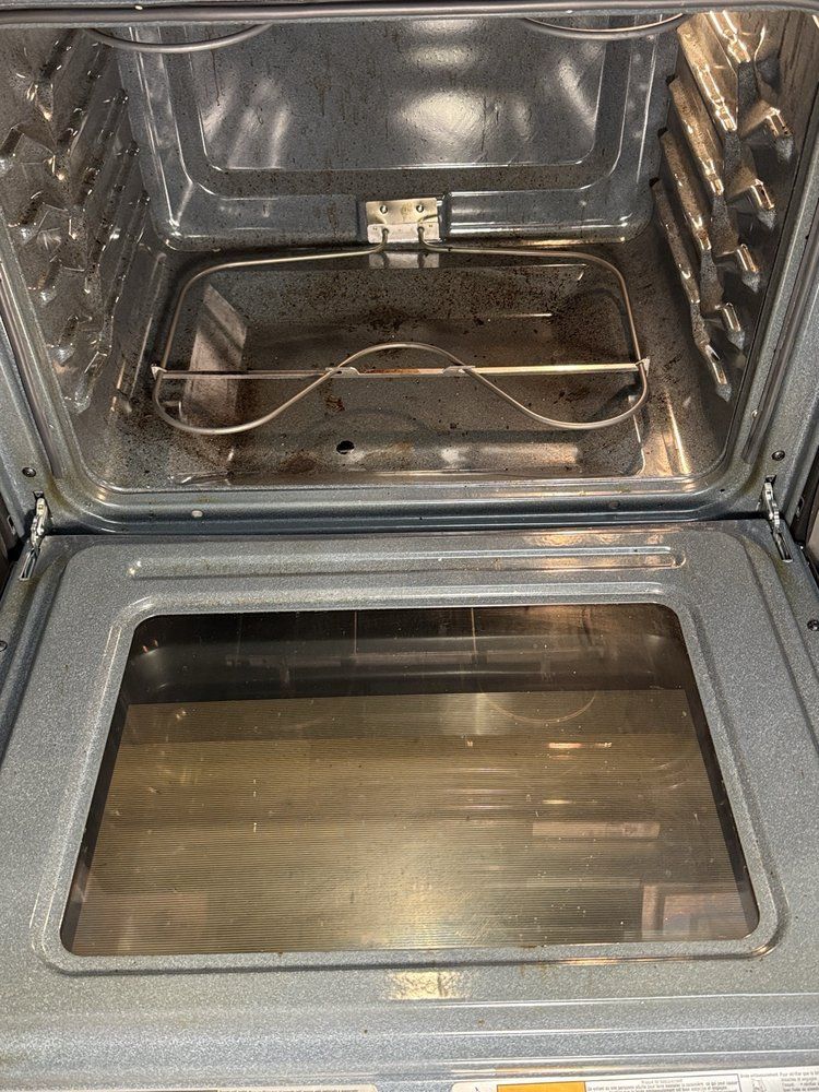 An open oven interior, showing racks and grime on the bottom. Glass door is visible.