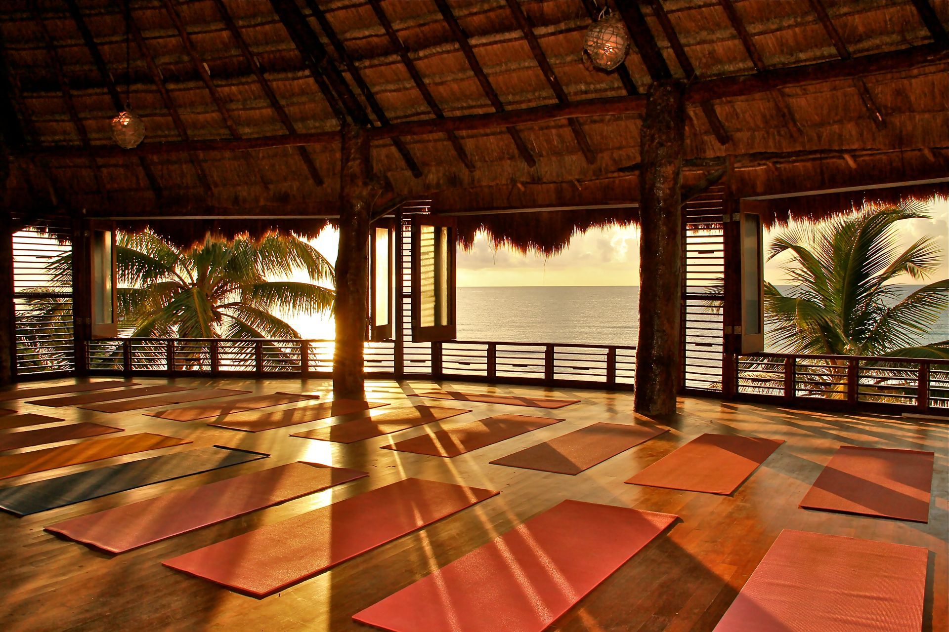 A yoga studio with a thatched roof and a view of the ocean