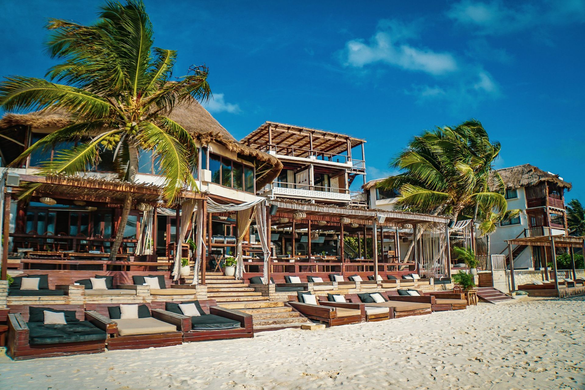 A large building with a lot of chairs on the beach in front of it.